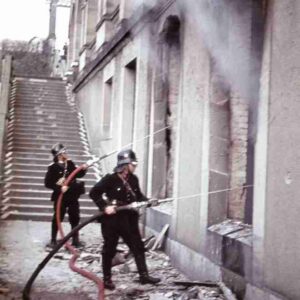 Two firemen fighting a fire after air raid on Kassel.