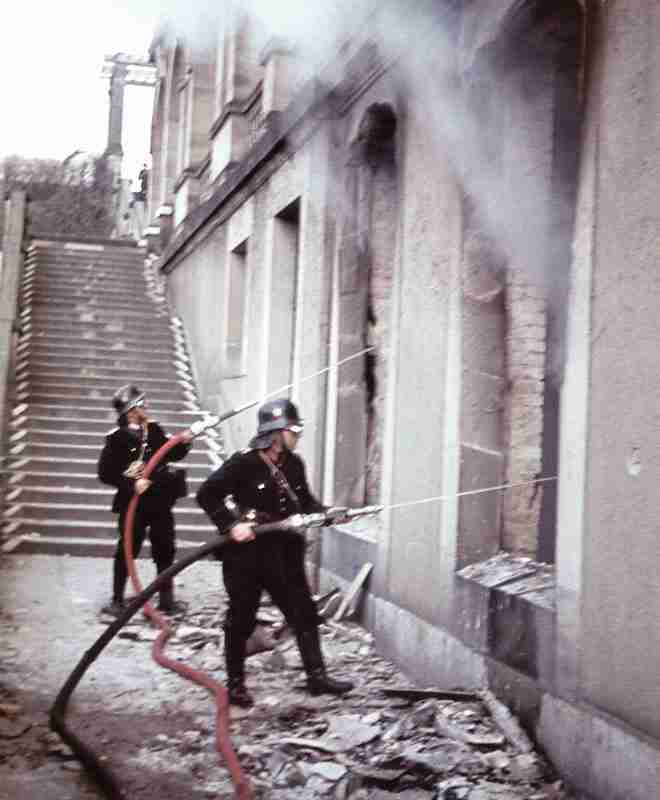 Two firemen fighting a fire after air raid on Kassel.