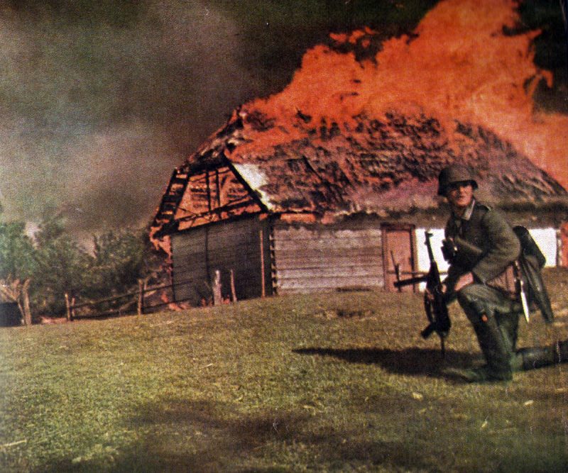 German NOC in front of a burning hut